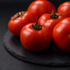 Delicious fresh juicy tomatoes on a dark concrete background Pomodoro Ailsa Craig